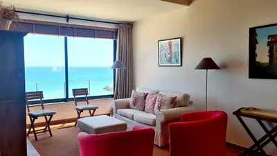 a living room with a couch and chairs and a large window at Albufeira Beach Cliffs House in Albufeira