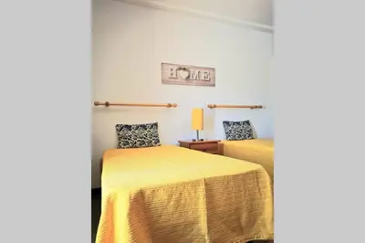a bedroom with two beds with yellow sheets and a lamp at Vila Planalto - Golfe - Entre o Golfe e o Mar in Vilamoura