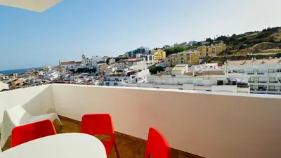 a balcony with red chairs and a view of a city at Rooftop by Check-in Portugal in Albufeira