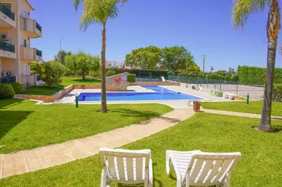 a yard with two white chairs and a swimming pool at Kamaleon Sol by Sunny Deluxe in Albufeira