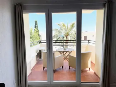 a room with a balcony with a table and chairs at Seaview Studio - 10 Min. Beach, Private Condo, Pool, Grill & Free Parking in Albufeira
