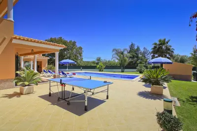 a patio with a ping pong table and umbrellas at Villa João Paulo in Albufeira