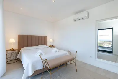 a white bedroom with a large bed and a window at Villa Tropicana in Albufeira