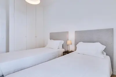 two beds in a room with white sheets at AL - Apartamento Egas Moniz in Quarteira