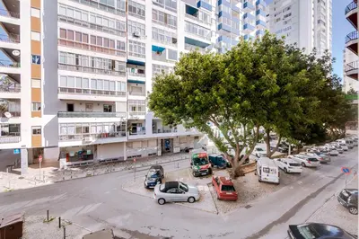 an overhead view of a parking lot with cars and a tree at AL - Apartamento Egas Moniz in Quarteira