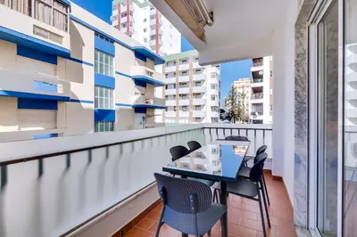 a balcony with a table and chairs in a building at AL - Apartamento Egas Moniz in Quarteira
