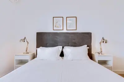 a bedroom with a white bed with two night stands at AL - Apartamento Egas Moniz in Quarteira