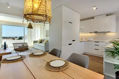 a kitchen and dining room with a wooden table and chairs at Apartamento Boavista - Sea View by DreamvillasAlbufeira in Albufeira