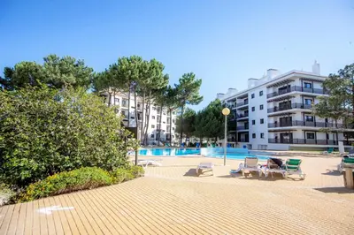 a courtyard with chairs and a building and a pool at T2 Apartment Falesia Beach Albufeira in Roja- Pé