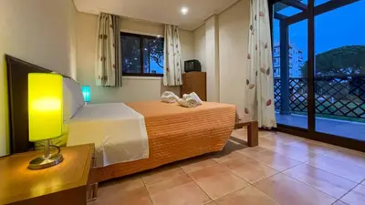 a bedroom with a bed with a lamp and a window at T2 Apartment Falesia Beach Albufeira in Roja- Pé