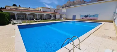 a swimming pool in front of a house at Sandy Beach apartment in Albufeira