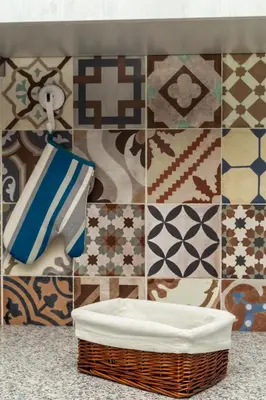 a bathroom with a tile wall with a basket and towels at Casa da Praia dos Pescadores in Albufeira