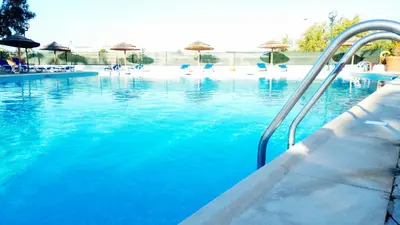 a swimming pool with blue water and umbrellas at Albufeira 603 in Albufeira