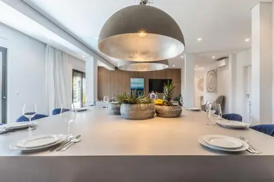 a white house with a deck with a table and chairs at Vila Hibisco by Garvetur in Vilamoura