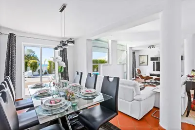 a dining room and living room with a table and chairs at Villa Maresia Dourada in Guia