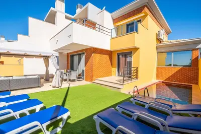 a lawn with blue chairs in front of a house at Cozy villa with pool and Barbecue in Albufeira