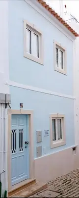 a white house with a blue door and two windows at Velha 34 in Albufeira