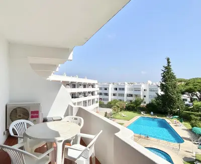a balcony with a table and chairs and a swimming pool at Alvaflor - Vilamoura in Vilamoura