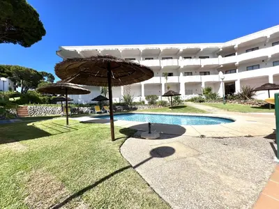 a pool with umbrellas in front of a building at Alvaflor - Vilamoura in Vilamoura