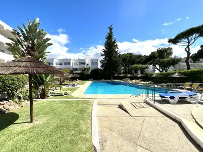 a swimming pool with an umbrella next to a resort at Alvaflor - Vilamoura in Vilamoura