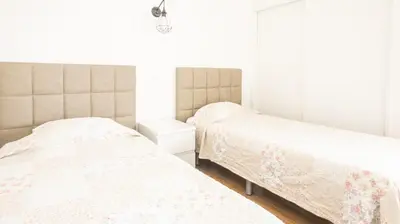 two beds in a bedroom with white walls at Apartamentos Pedro for Families by Bedzy in Albufeira