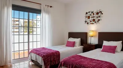 a hotel room with two beds and a purse on the bed at Villa do Mar - Galé in Albufeira