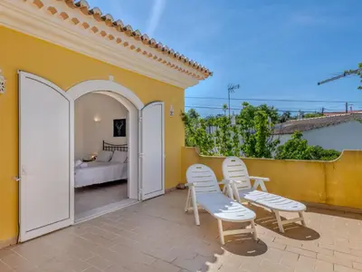 a patio with two chairs and a bed on a yellow wall at Villa Villa Monte da Torre by Interhome in Loulé