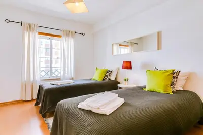 two beds in a room with yellow and green pillows at The Nest Apartment - Sea View - Faro in Faro