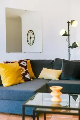 a living room with a blue couch with yellow pillows at The Nest Apartment - Sea View - Faro in Faro