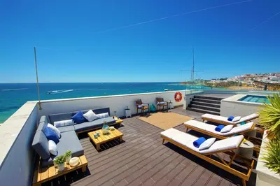 a balcony with couches and a view of the ocean at Casa da Bandeira -Perfect Location-Beach front- Rooftop Pool by DreamvillasAlbufeira in Albufeira