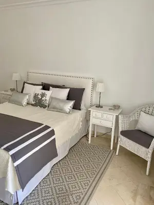 a bedroom with a bed and a chair and a table at Beautiful apartment for rent in Quinta do Lago with excellent resort facilities close to lake and beach. in Quinta do Lago