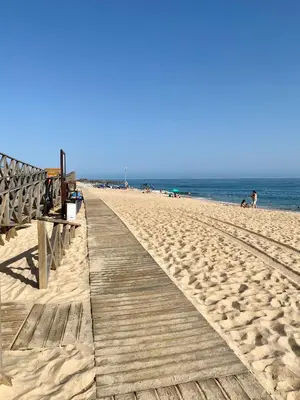 a wooden boardwalk on a beach with people on it at Beautiful apartment for rent in Quinta do Lago with excellent resort facilities close to lake and beach. in Quinta do Lago