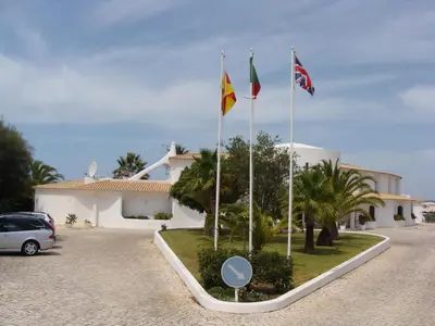 three flags on poles in front of a building at FLOR DO VALE - APARTAMENTOS TURISTICOS in Guia