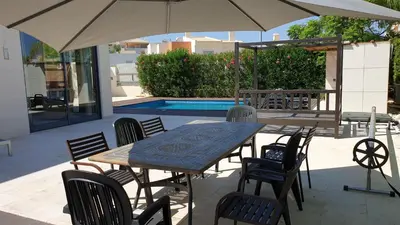 a table and chairs with an umbrella next to a pool at Luxury city Villa Olivia 10 - 15 min to the Beach Oura, private swimming pool in Albufeira
