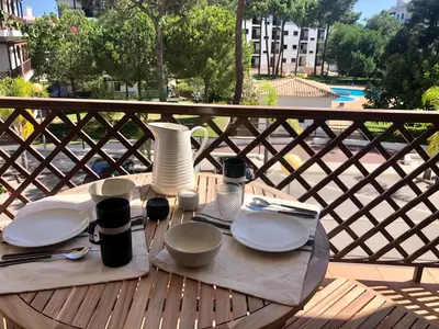 a table with plates and utensils on top of a balcony at Praia da Falésia - Falesia Beach - Apartment Pine Sun Park in Albufeira