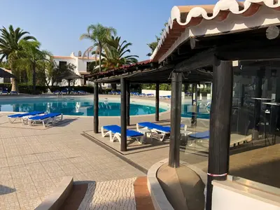 a swimming pool with blue lounge chairs and a building at Appartement Sao Rafael praia Algarve portugal in Albufeira