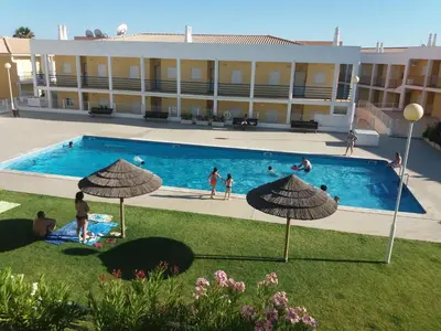a group of people in a swimming pool with umbrellas at Encosta S. José -Vale Parra in Albufeira