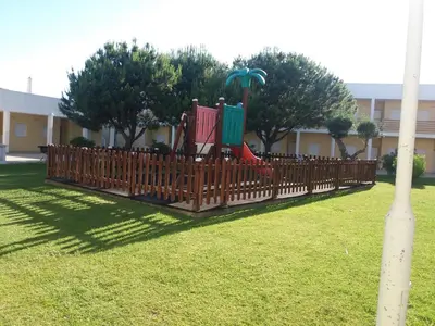 a backyard with a lawn and plants in front of a building at Encosta S. José -Vale Parra in Albufeira