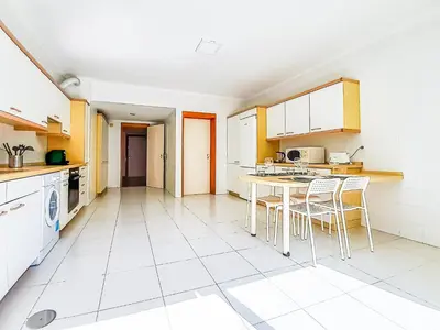a kitchen with white appliances and a table and chairs at Por do Sol Dourado T2 HsR Vilamarina in Vilamoura