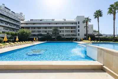 a swimming pool in front of a building at Por do Sol Dourado T2 HsR Vilamarina in Vilamoura