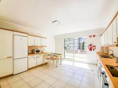 a kitchen with white cabinets and a table in it at Por do Sol Dourado T2 HsR Vilamarina in Vilamoura