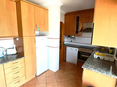 a kitchen with wooden cabinets and a white refrigerator at Vila Falesia Penthouse in Albufeira