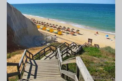 a wooden staircase leading to a beach with umbrellas at Falesia - near the beach - The GAVEL Apartment in Albufeira