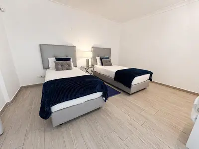 a bedroom with a white bed with a black blanket and pillows at Villa Cristina 17 - 500 m from the Beach in Albufeira