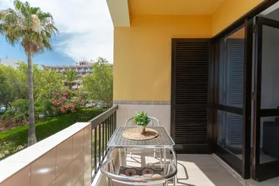 a table on a balcony with a view of a palm tree at Elma By Albufeira Rental in Albufeira