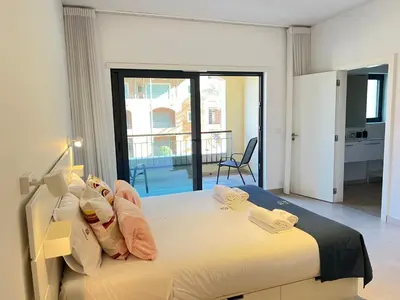 a bedroom with a large bed and a balcony at Gardens Side By FHR piscina, parking in Quarteira