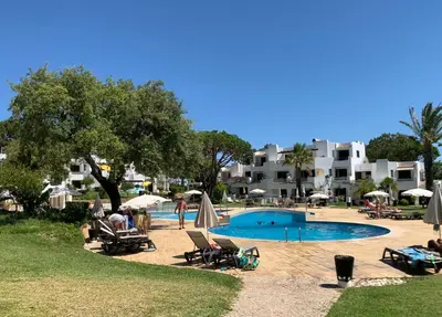 a pool with chairs and umbrellas in a resort at Casa da Balaia - beach, pool, golf and tennis in Albufeira