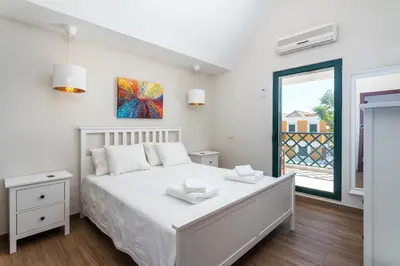 a white bedroom with a bed and a window at Holiday house in elite residential area of Faro in Faro