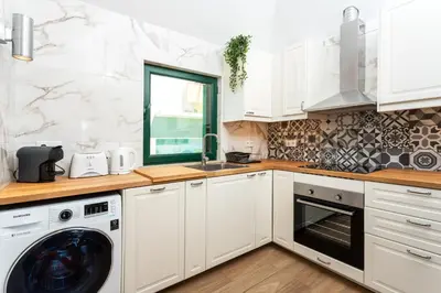 a kitchen with white cabinets and a washer and dryer at Holiday house in elite residential area of Faro in Faro