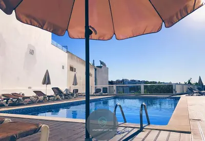 a swimming pool with an umbrella and chairs next to it at Apartment Sant'Ana Old Town Albufeira - Bay View in Albufeira